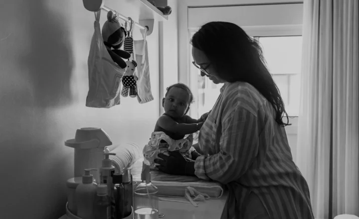 Mãe trocando a roupa do bebê no trocador, em preto e branco